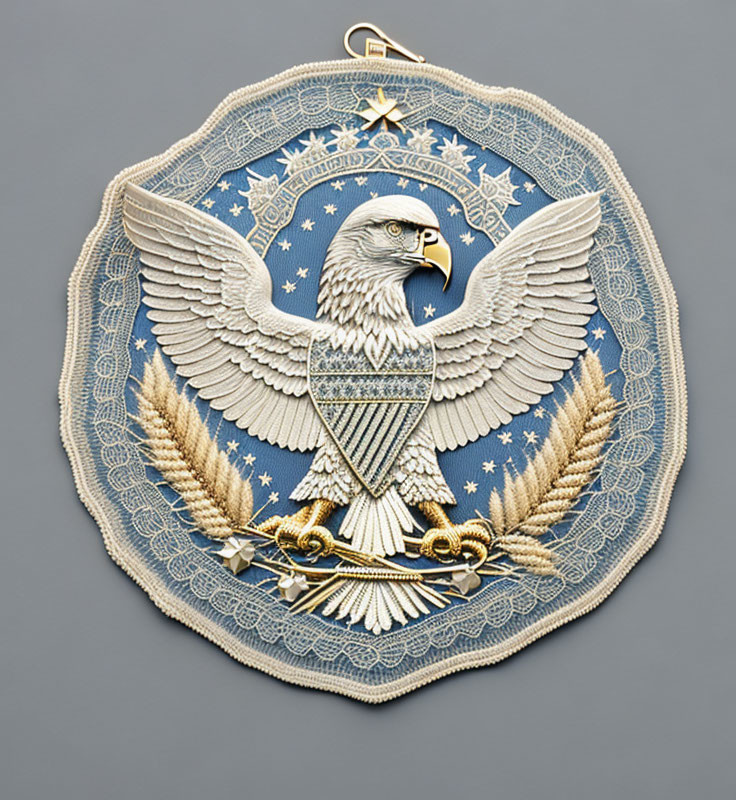 Embroidered eagle badge with shield, stars, and wheat sheaves on blue background