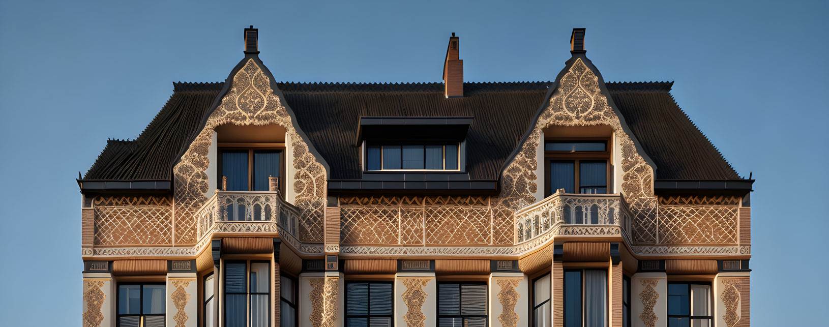 Symmetrical building facade with lace-like patterns and balcony under clear sky