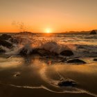 Vibrant sunset over turbulent sea with crashing waves and rocky shore