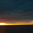 Tranquil sunset over serene sea with orange and blue sky.