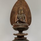 Intricate Buddha statue in meditation with flame aureole on decorative pedestal