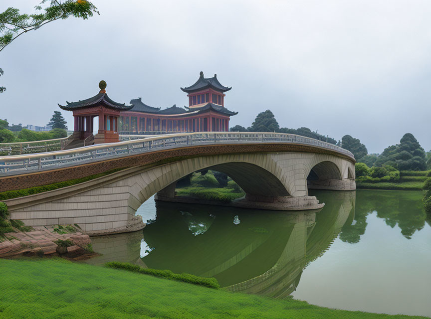 Scenic traditional Chinese-style bridge with red pavilions and curved arches over calm water amidst lush