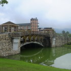 Scenic traditional Chinese-style bridge with red pavilions and curved arches over calm water amidst lush