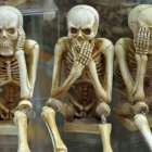 Three Skeletons in Various Poses Against Desolate Background