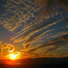 Tranquil sunset scene with radiant sun and golden-edged clouds