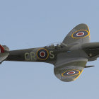 Vintage Military Aircraft with Camouflage Paint and Roundels Flying in Clear Blue Sky