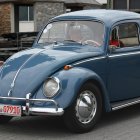 Vintage Blue Volkswagen Beetle Among Classic Cars on Dirt Road