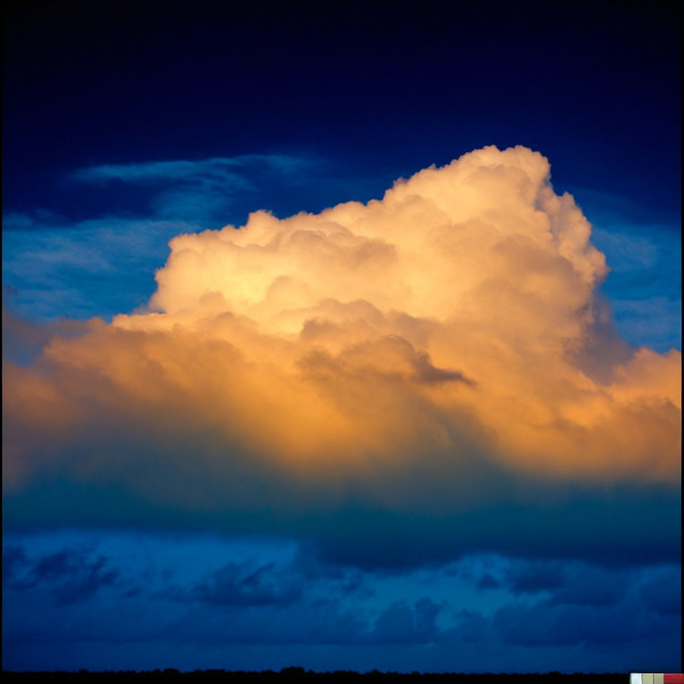 Dramatic cumulus cloud in golden sunlight against stormy twilight sky