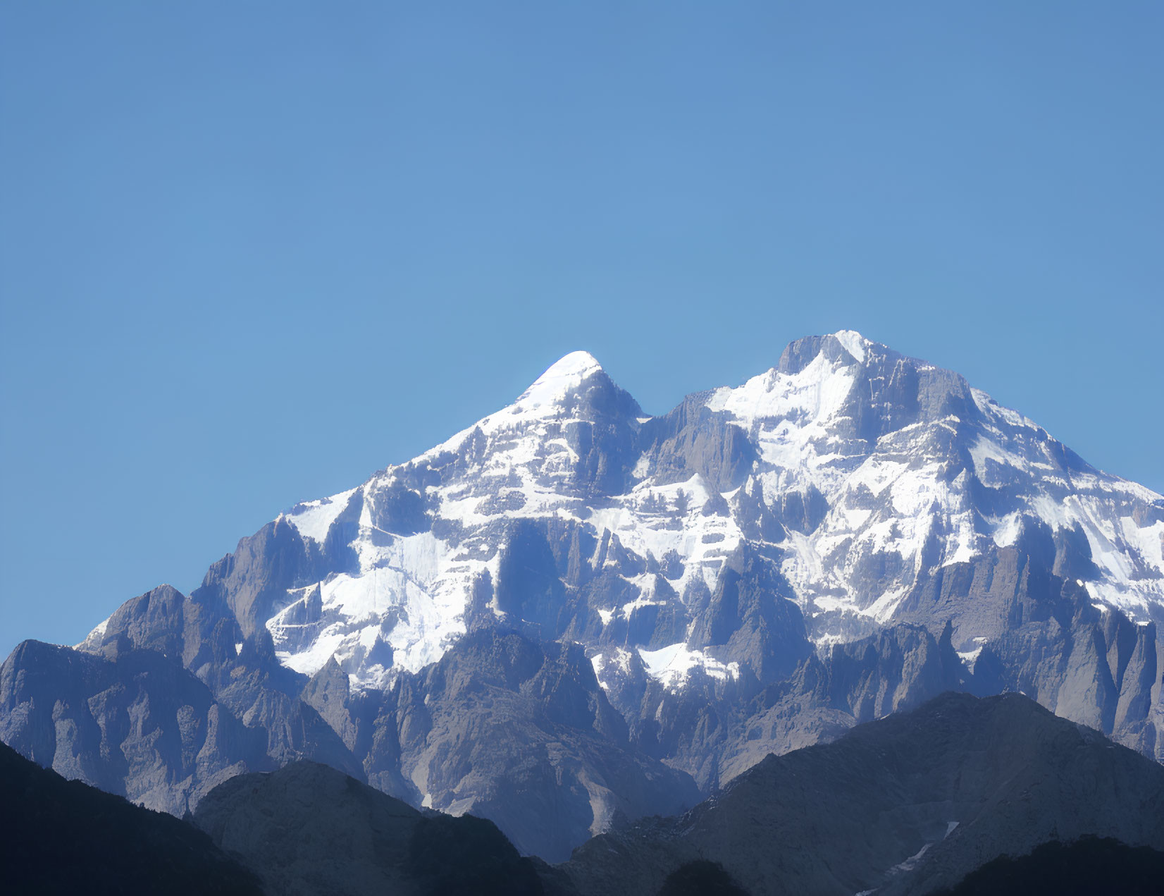 Snow-Capped Mountain Peaks Over Rocky Foothills and Blue Sky