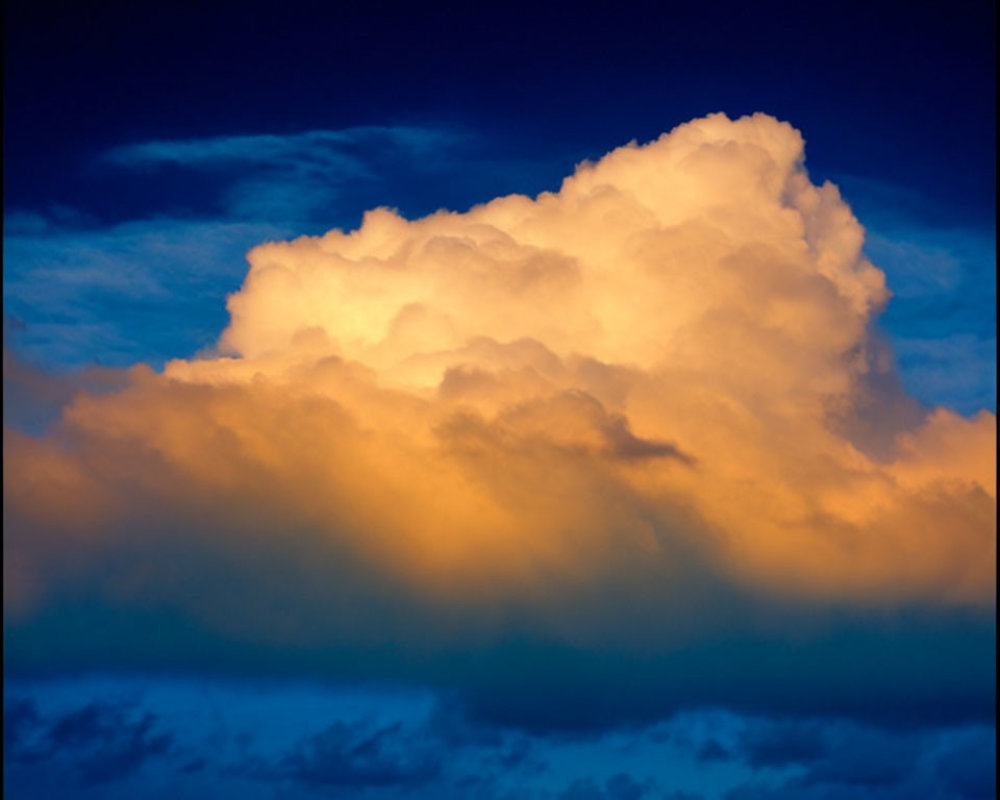 Dramatic cumulus cloud in golden sunlight against stormy twilight sky