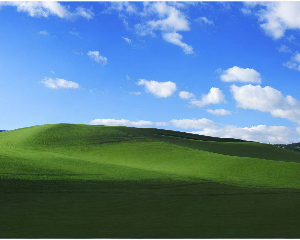 Scenic view of rolling green hills under vibrant blue sky