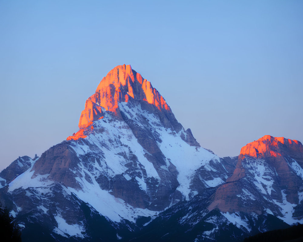 Sunset Alpenglow on Snowy Mountain Peak against Clear Blue Sky