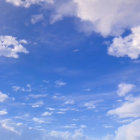 White fluffy clouds in serene blue sky with pink edges