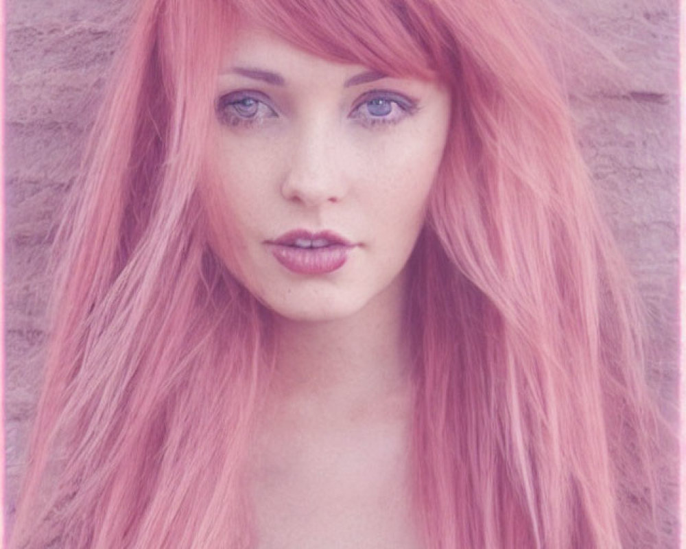 Woman with Pink Hair and Blue Eyes Against Pink Brick Wall