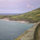 Scenic winding road on lush cliff by turbulent sea