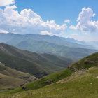 Solitary figure in green hills under cloudy sky with mountains