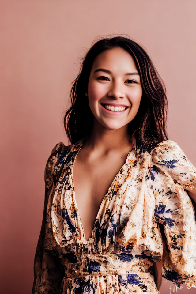 Smiling woman in floral dress on pink background