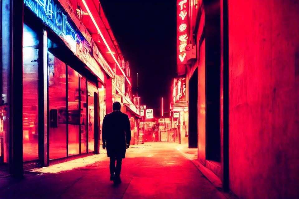 Solitary figure walking on neon-lit street at night