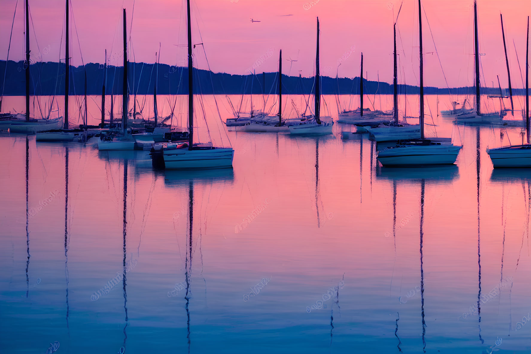 Sailboats moored on calm waters at dusk with purple and orange sky reflections