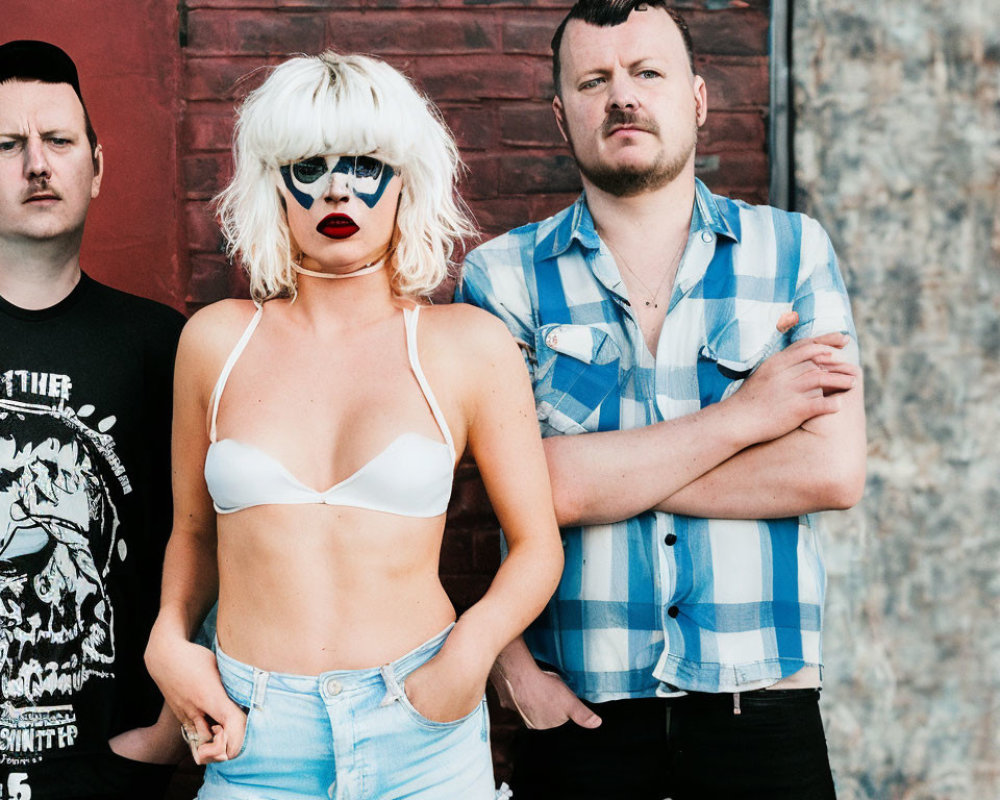 Three Stylish Individuals Posing Against Red Wall