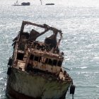 Multicolored shipwreck in icy waters with distant ships and cloudy sky