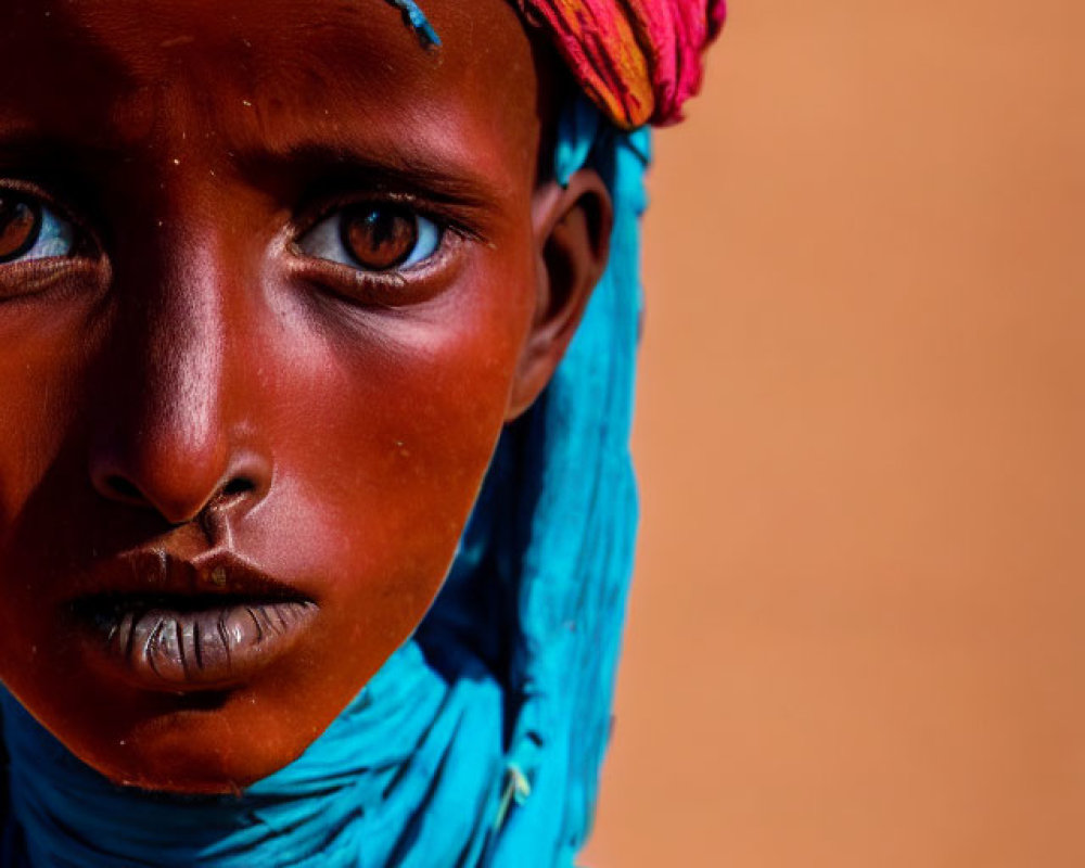 Vibrant turquoise and pink headwear on intense gaze portrait