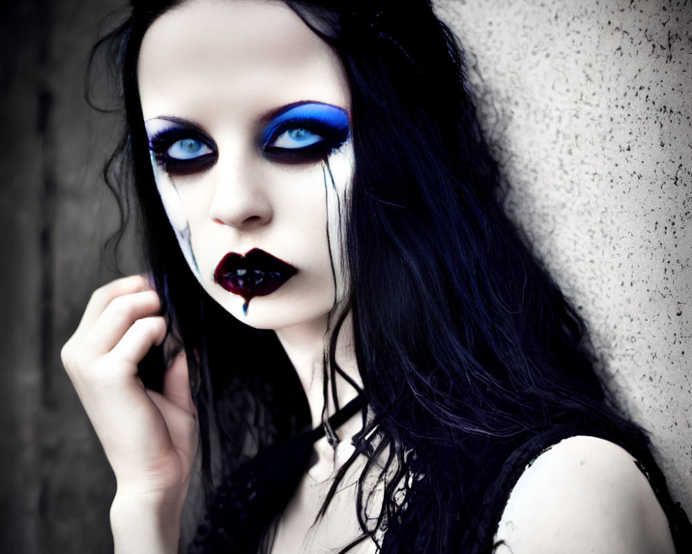 Woman with Dark Makeup and Blue Eyeshadow Against Grey Wall