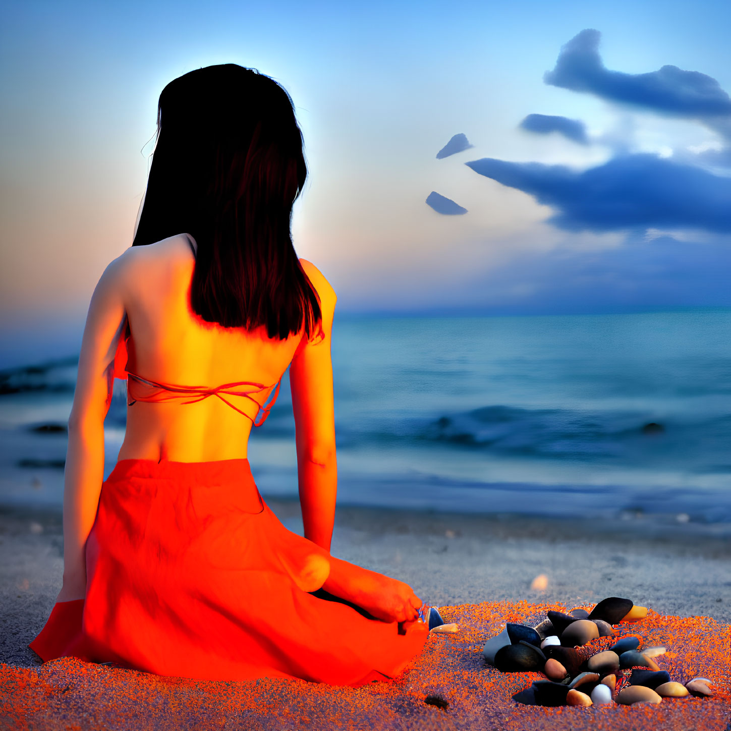 Woman in Orange Dress Sitting on Beach at Sunset with Pebbles, Birds, and Sea View