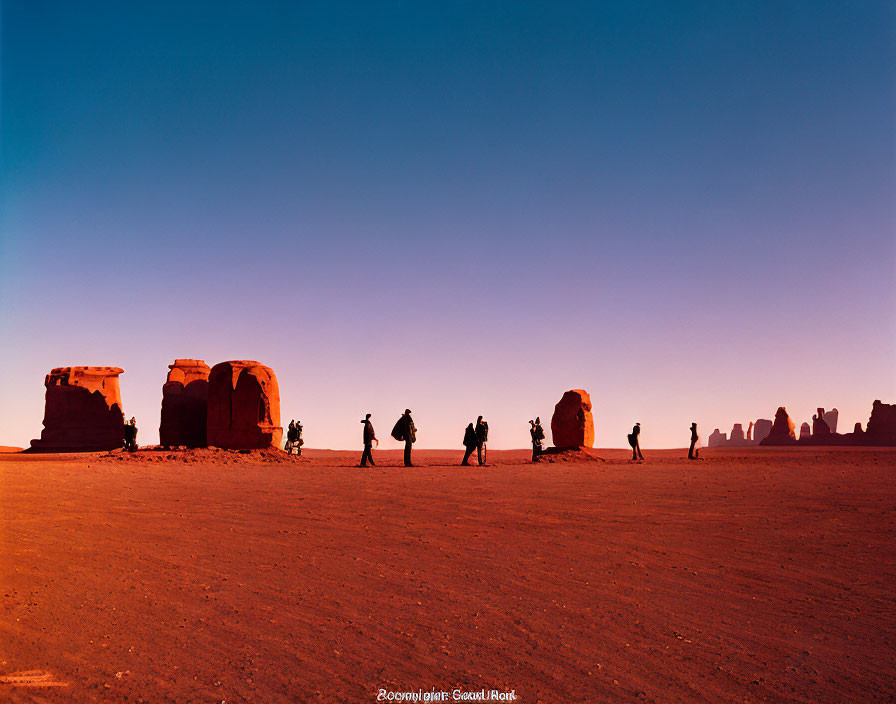 Silhouetted People Walking Among Rock Formations at Dusk or Dawn