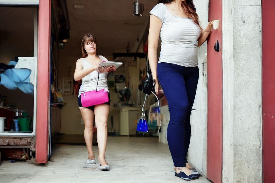 Two women in doorway, one with papers, the other with handbag, having casual conversation