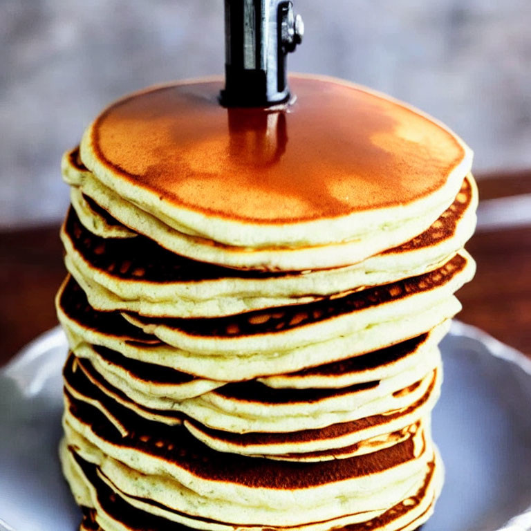 Golden Brown Pancakes with Pouring Syrup on Plate