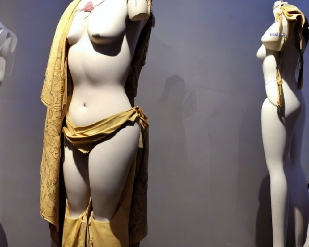 Mannequins in Yellow Toga-Like Outfit & Undressed Garments Displayed in