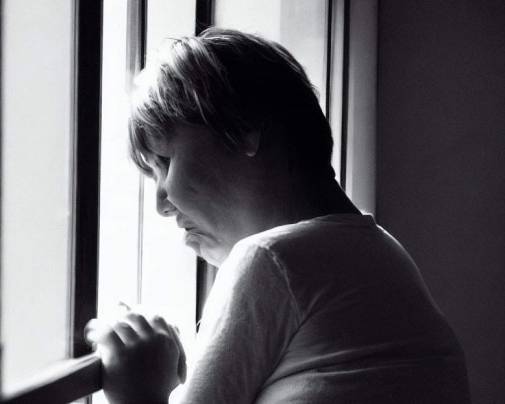 Monochrome portrait of person with short hair gazing out window