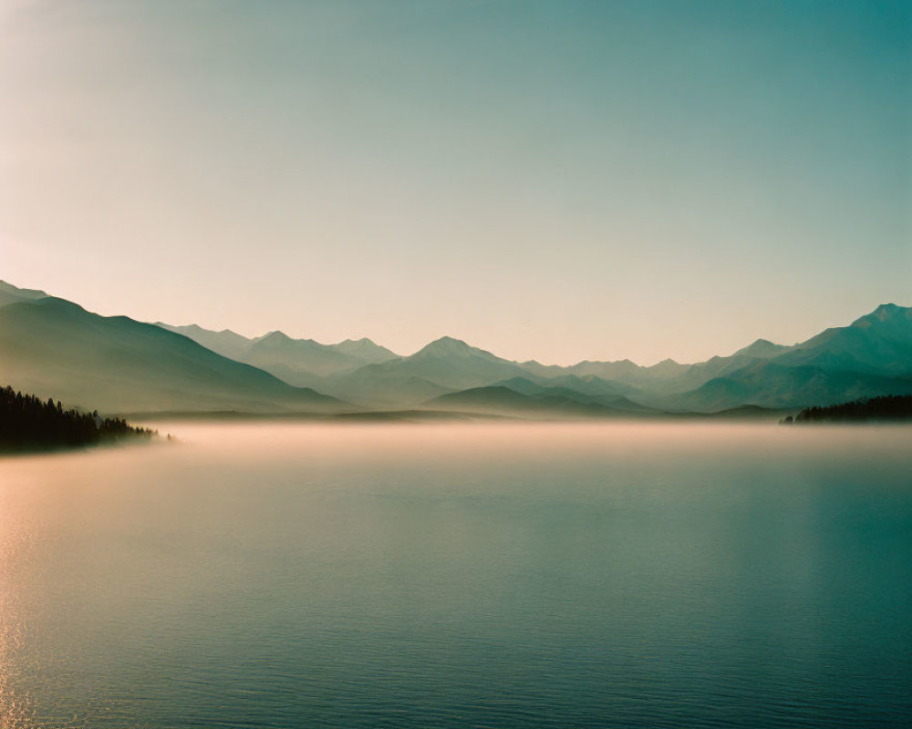 Tranquil Lake Surrounded by Misty Mountains at Dusk