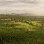 Scenic landscape with twin peaks, river, village, and rolling hills