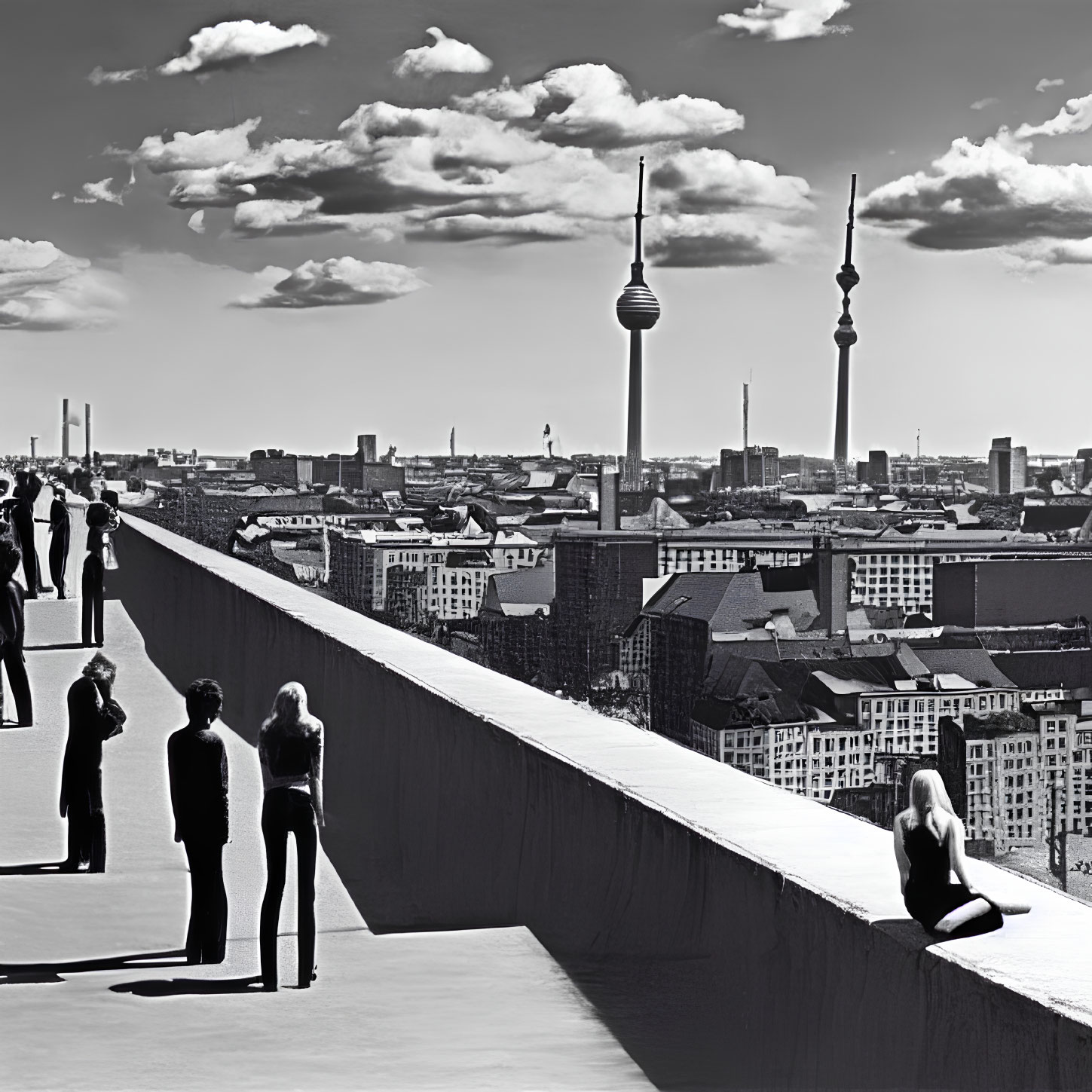 Monochrome cityscape with people on high vantage point overlooking twin towers skyline.