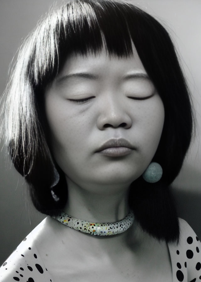 Monochrome portrait of woman with eyes closed, bob haircut, polka dot top