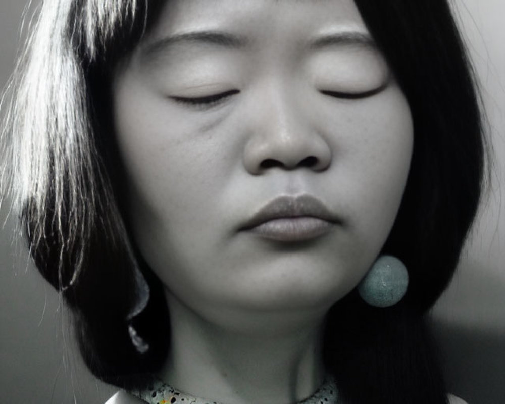 Monochrome portrait of woman with eyes closed, bob haircut, polka dot top