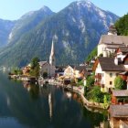 Scenic Alpine village with chalet houses, church, lake, mountains, and flora