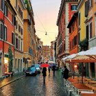 Quaint town street scene with people and colorful umbrellas on rain-soaked cobblestones