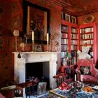 Luxurious red-themed library room with fireplace, armchair, bookshelves, and ornate decor