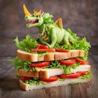 Toy dragon on sandwich with lettuce, tomatoes, and condiments