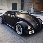 Vintage Black Car with Exposed Engine Parked in Front of Ornate Building