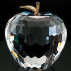 Glass apple sculpture with floral designs and gold accents on dark background