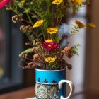 Blue and Gold Teacup with Pink and Yellow Flowers on Wooden Surface