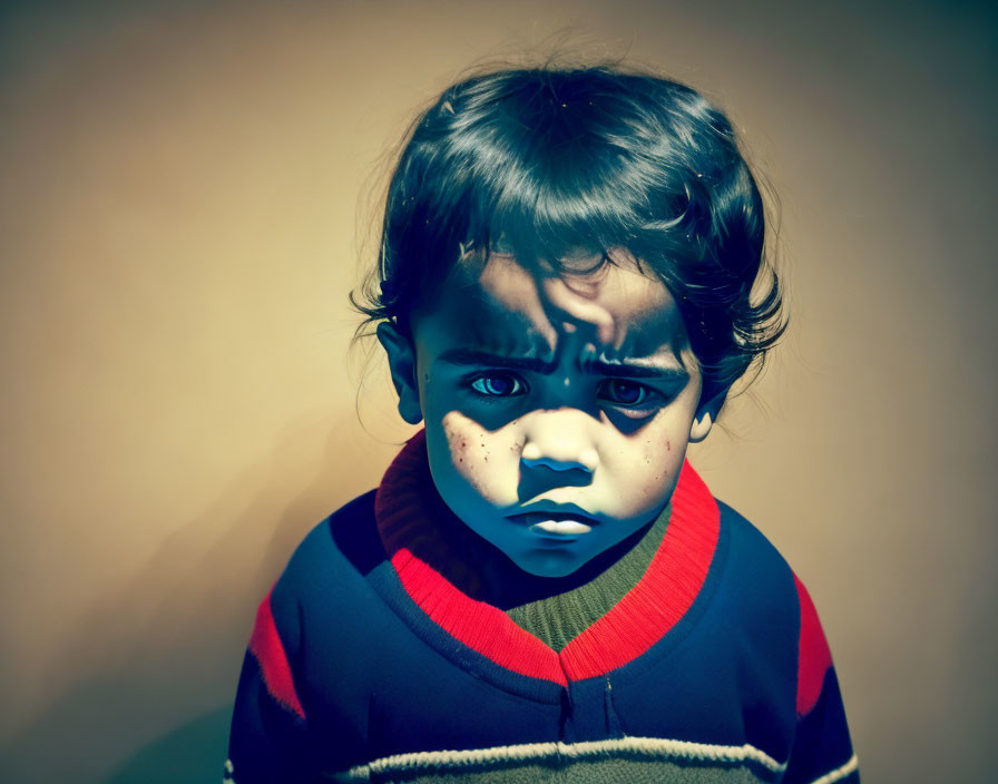 Serious young child with painted face in striped sweater