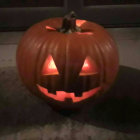 Sinister-faced glowing jack-o'-lantern in misty, shadowy scene