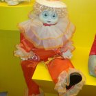 Vintage Clown Doll in White and Orange Costume on Yellow Floral Background