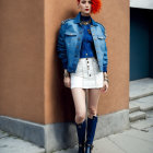 Stylish person with red hair, denim jacket, white skirt, black boots against blue-accent