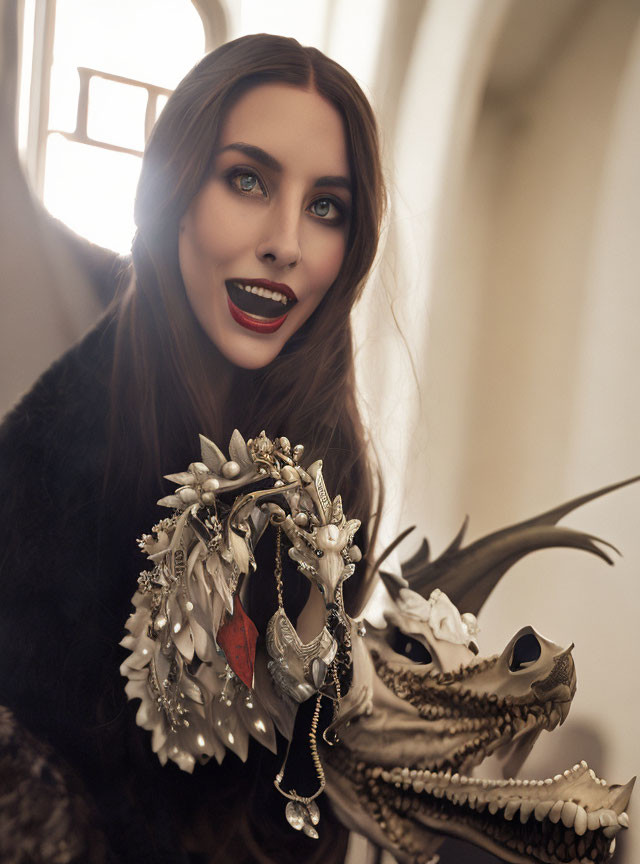 Woman with blue eyes holding silver dragon skull with jewel.